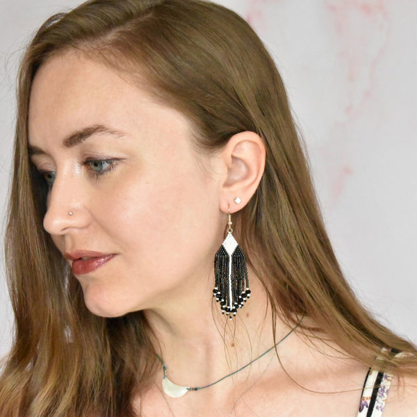 hand beaded black and white delica fringe earrings with geometric triangle and diamond design and swarovski crystals shown on person